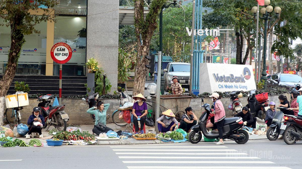 Người dân họp chợ ngay dưới biển cấm họp chợ. (ảnh chụp 18 giờ 00, ngày 25-3-2026).