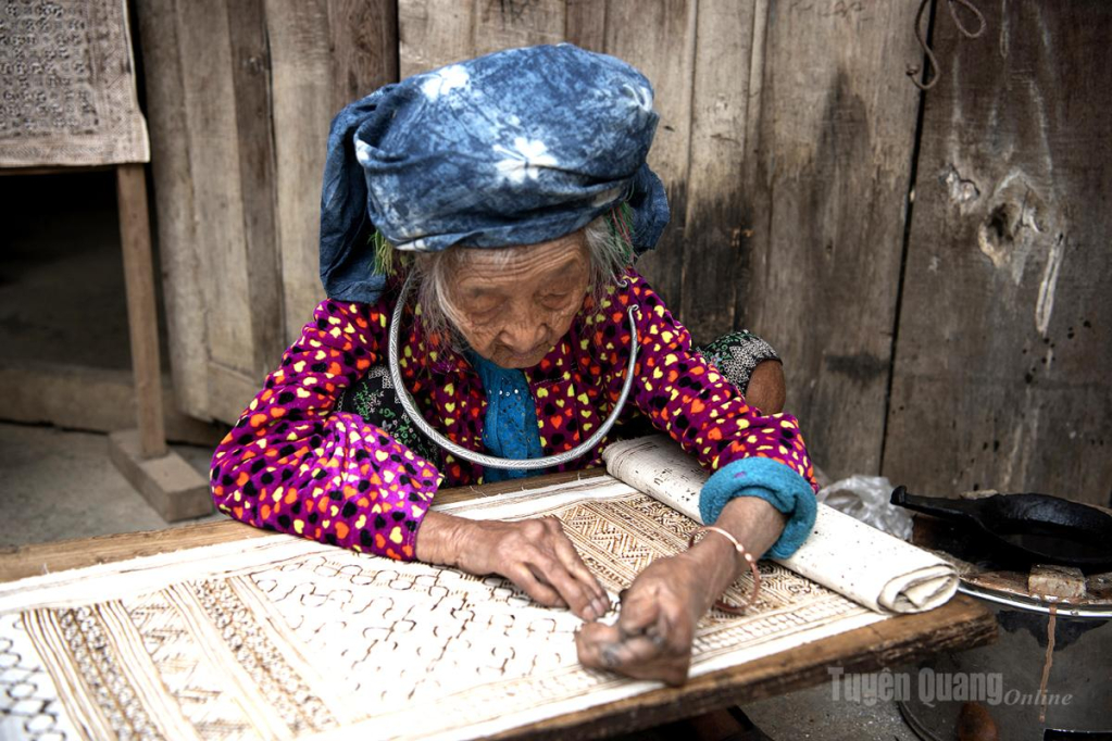 Nghệ nhân người Mông tỉ mỉ vẽ sáp ong trên nền vải lanh, tạo nên những hoa văn truyền thống đặc trưng của dân tộc Mông.