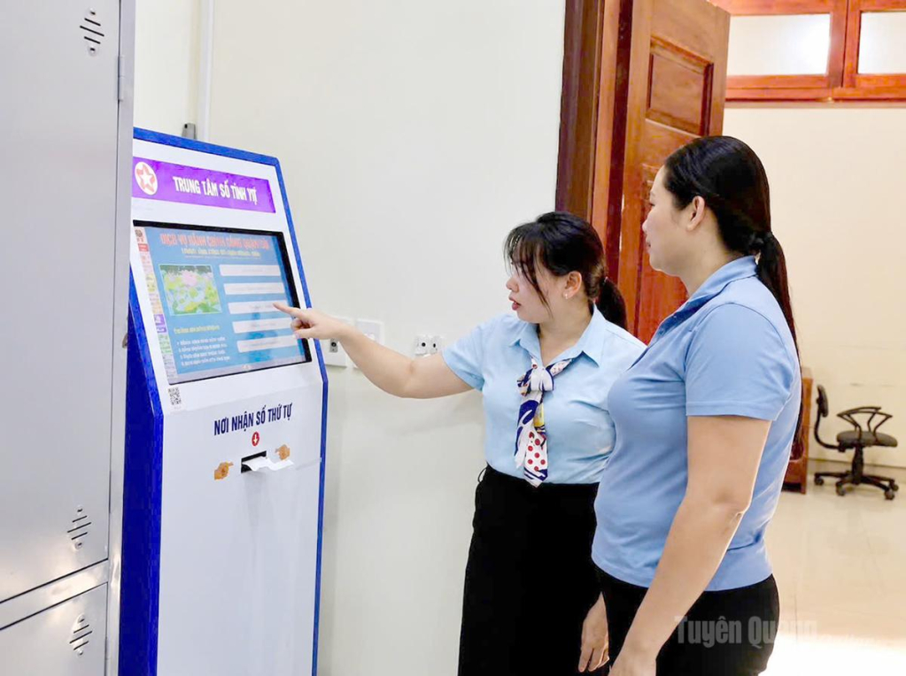 Chuyên viên Trung tâm Phục vụ hành chính công xã Lâm Bình hướng dẫn người dân lấy số thứ tự trên máy tự động để  giải quyết thủ tục hành chính.