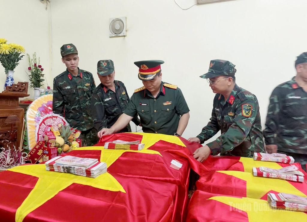 Đại tá Nguyễn Minh Khôi, Phó Chính ủy Bộ Chỉ huy Quân sự tỉnh cùng cán bộ, chiến sĩ Đội Tìm kiếm, quy tập hài cốt liệt sĩ thực hiện nghi thức phủ Quốc kỳ lên hài cốt các anh hùng, liệt sĩ.