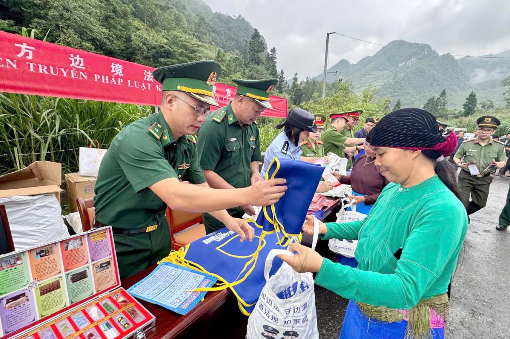 Cán bộ Đồn Biên phòng Phó Bảng phát tờ rơi và nhu yếu phẩm cho người dân khu vực biên giới.