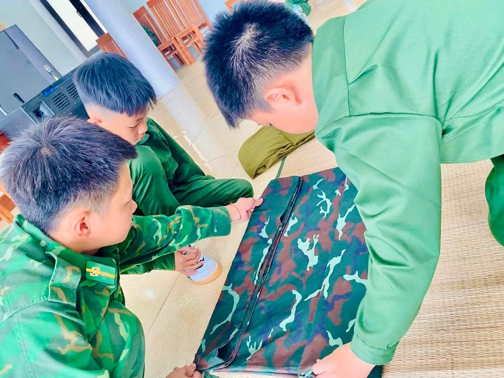 2. Dưới sự hướng dẫn của cán bộ huấn luyện, các học viên làm quen với nếp sống chính quy, bắt đầu từ việc gấp chăn màn gọn gàng, vuông vức.
