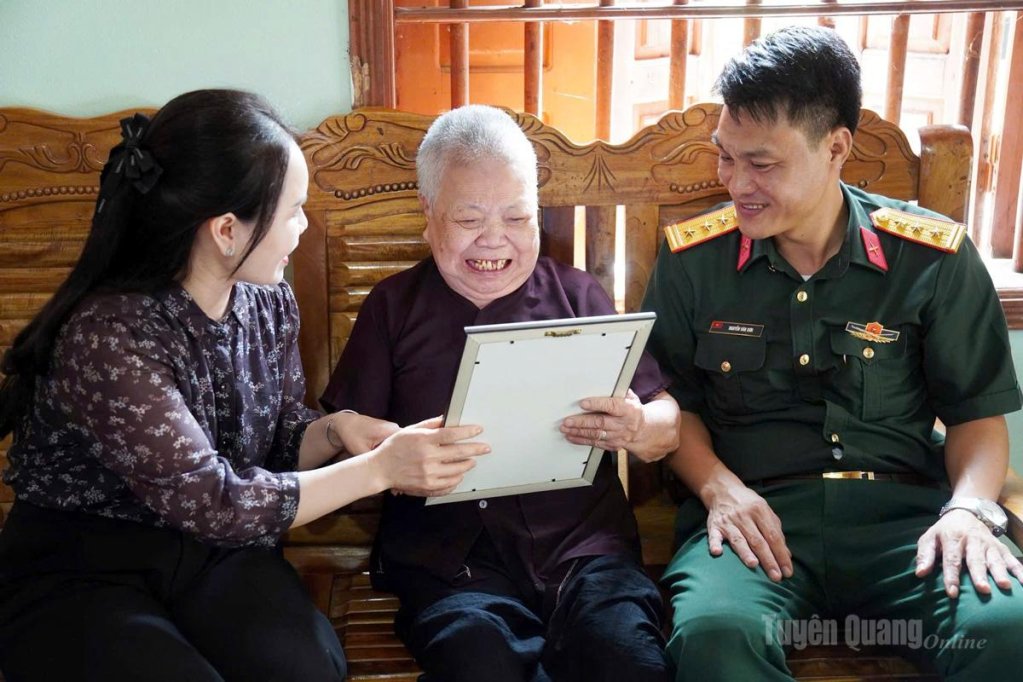 Lãnh đạo Đảng ủy cùng Ban CHQS xã Sơn Dương trao tặng ảnh chân dung phục chế cho bà Hoàng Thị Đức, là vợ liệt sĩ Lâm Văn Hội, trú tại thôn Phú Lộc, xã Sơn Dương.
