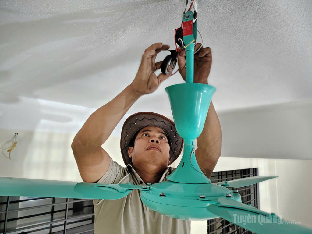 Bên trong các phòng học đã hoàn thiện cơ bản các hạng mục, anh Hà Văn Lường, công nhân tổ điện nước đang lắp đặt những chiếc quạt trần cẩn thận.