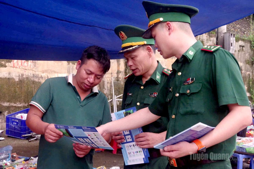 Cán bộ Đồn Biên phòng Bạch Đích phát tờ rơi cho người dân tại chợ Bạch Đích.